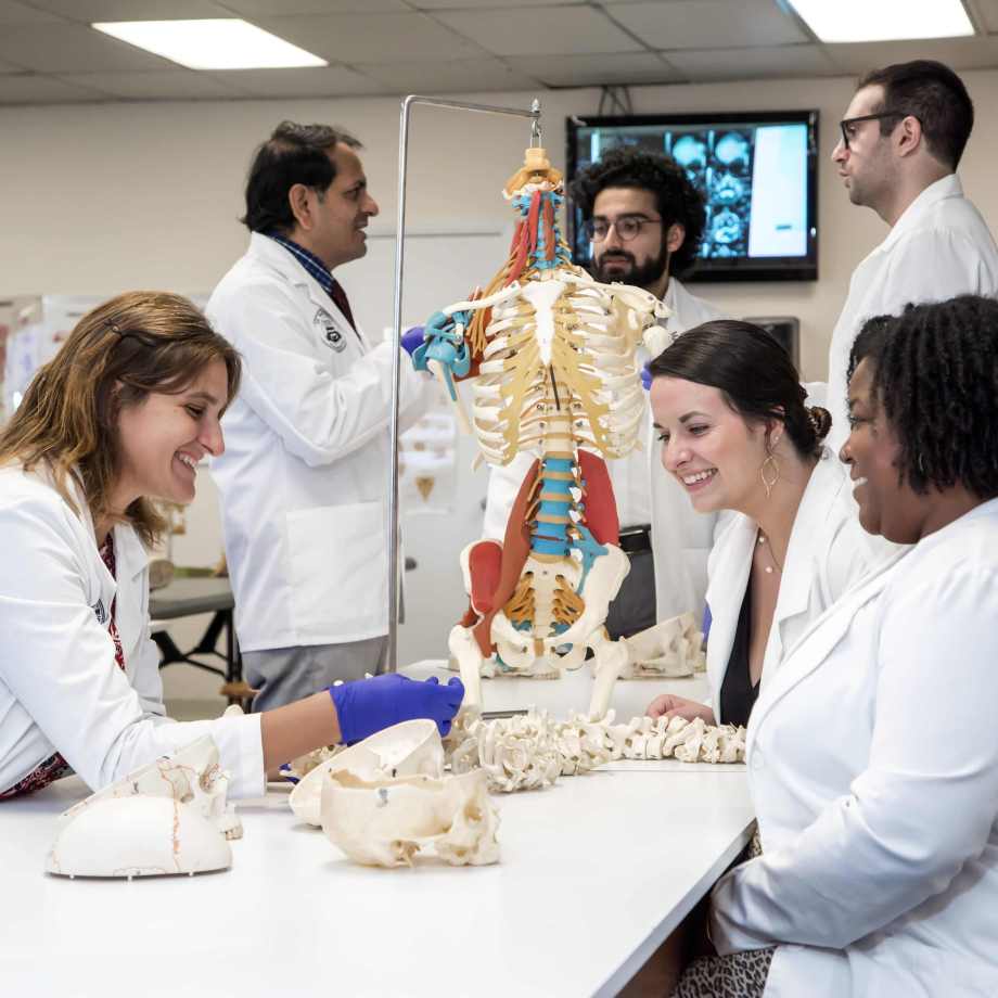 Students in their white coats, analysing a body