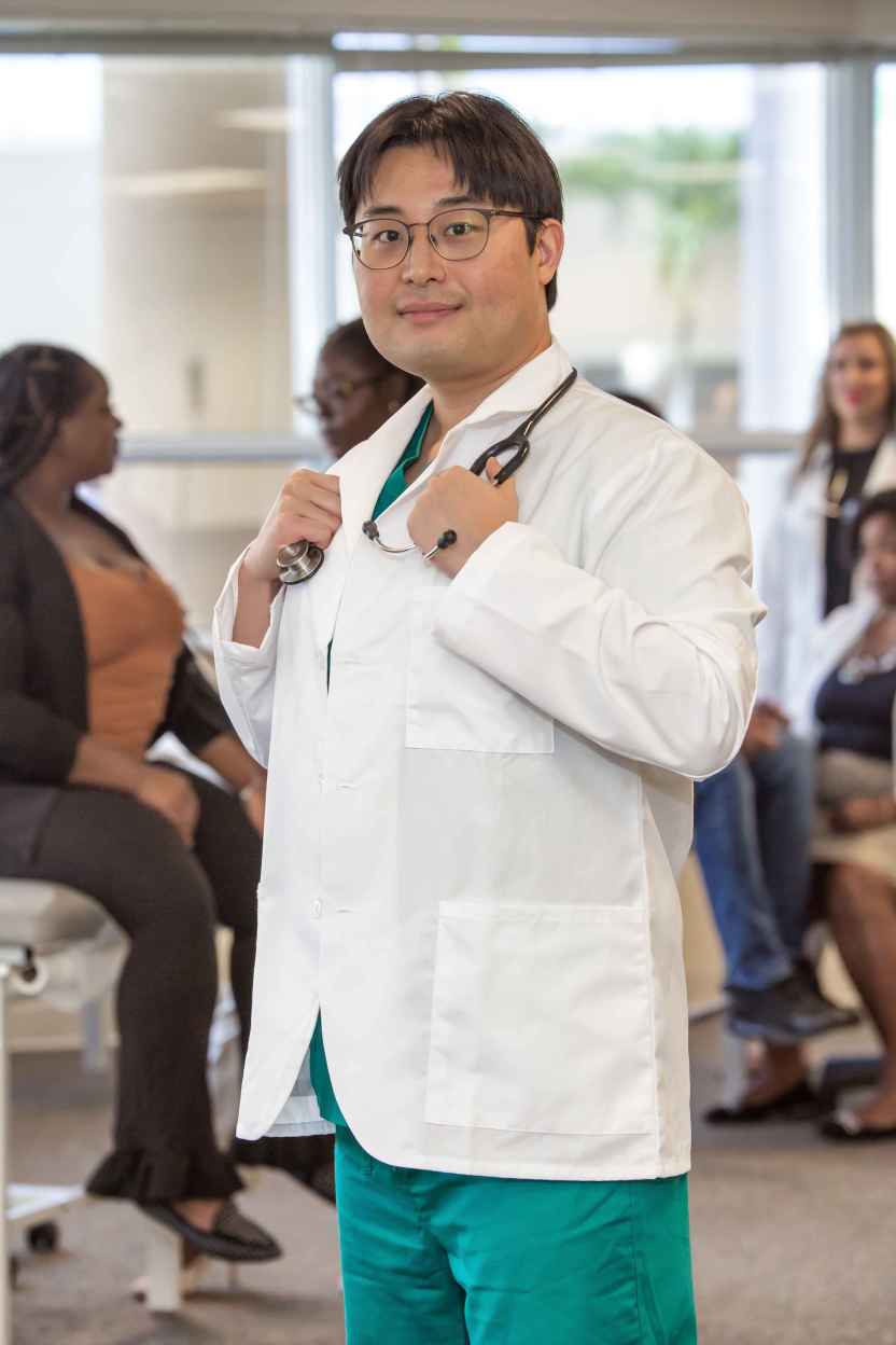 Wonjun Choi - SMU MED Student wearing his white coat in a classroom.
