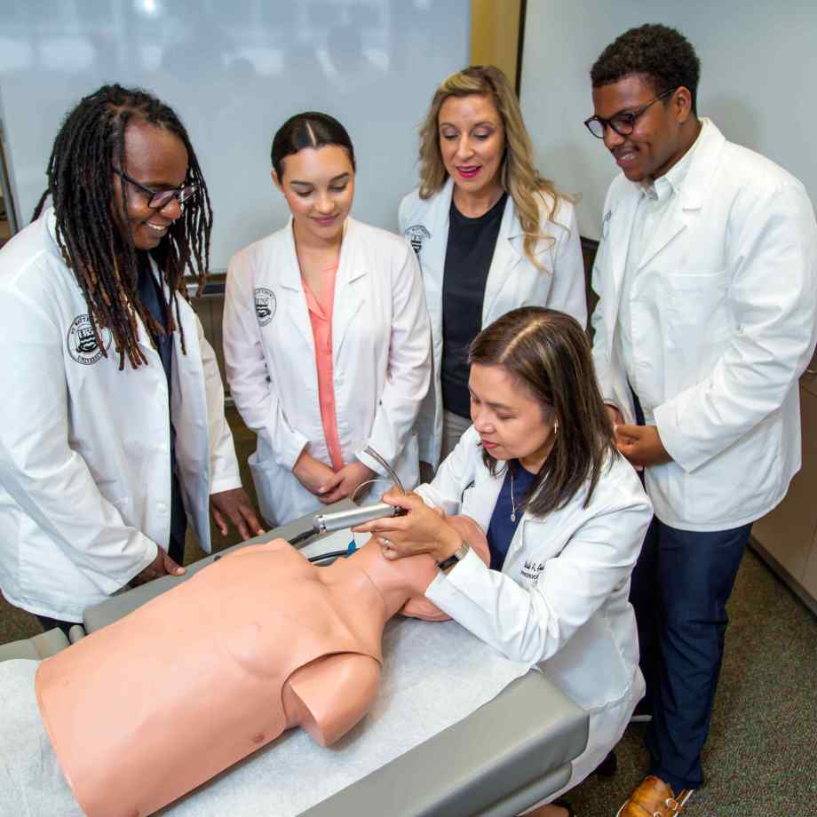 Image of medical students and a professor in a lab with dummy.