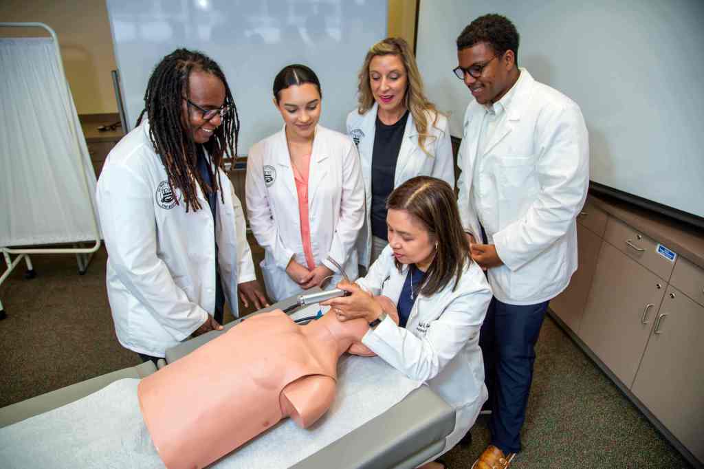 Image of medical students and a professor in a lab with dummy.
