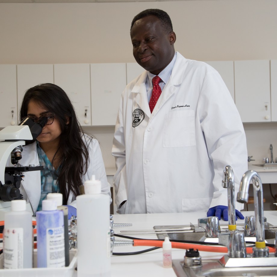 SMU Medical student working with microscope with faculty member assistance