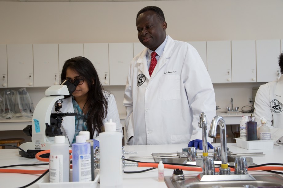 SMU Medical student working with microscope with faculty member assistance